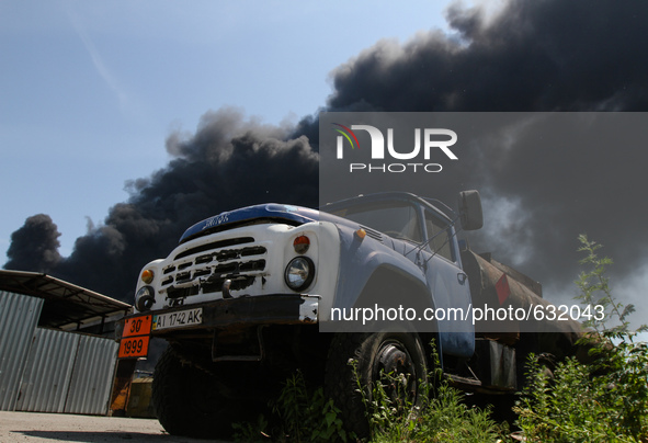 An old gas-tank truck is seen under a dark cloud of smoke after fuel storage terminal burning near Kyiv, June 9, 2015. 
