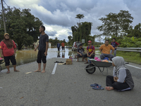 Stranded residents wait for food supplies on a submerged road by floodwaters following heavy monsoon rains in Temerloh, Pahang state of Mala...
