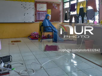 A woman pray inside a school classroom where residents take shelter from flooded house following heavy monsoon rains in Temerloh, Pahang sta...