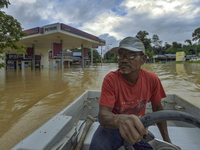 A man ride a boat past a fuel station submerged by floodwaters following heavy monsoon rains in Temerloh, Pahang state of Malaysia on Januar...
