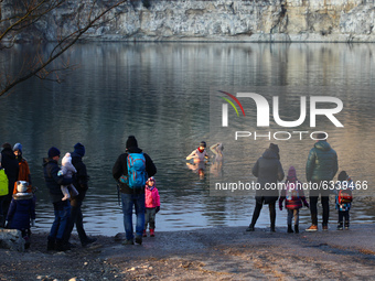 People watch winter swimmers dip in cold waters of Zakrzowek lake, a former limestone quarry located close to the city center in Krakow, Pol...