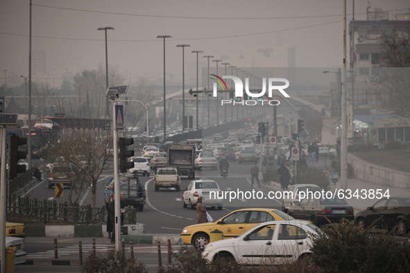 An Iranian woman wearing a protective face mask crosses an avenue in western Tehran during a polluted air, following the COVID-19 outbreak i...
