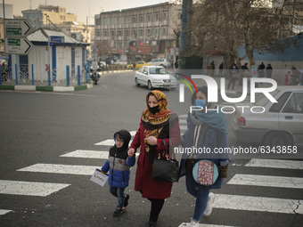 An Iranian family wearing protective face masks cross an avenue in northern Tehran during a polluted air, following the COVID-19 outbreak in...