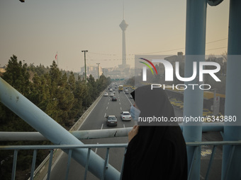 An Iranian veiled woman wearing a protective face mask walks on a bridge in northern Tehran during a polluted air, following the COVID-19 ou...