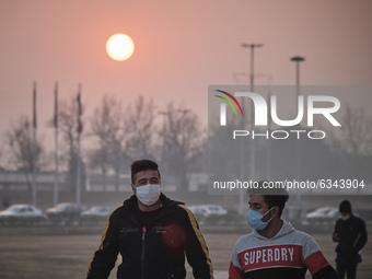 Two Iranian men wearing protective face masks walk along the Azadi (Freedom) Square in western Tehran during a polluted air, following the C...