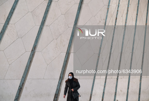 An Iranian woman wearing a protective face mask walks along the Azadi (Freedom) Square in western Tehran during a polluted air, following th...