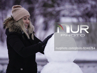 A woman builds a snowman with freshly fallen snow in the Royal Baths park in Warsaw, Poland on January 13, 2021. Though temperatures normall...