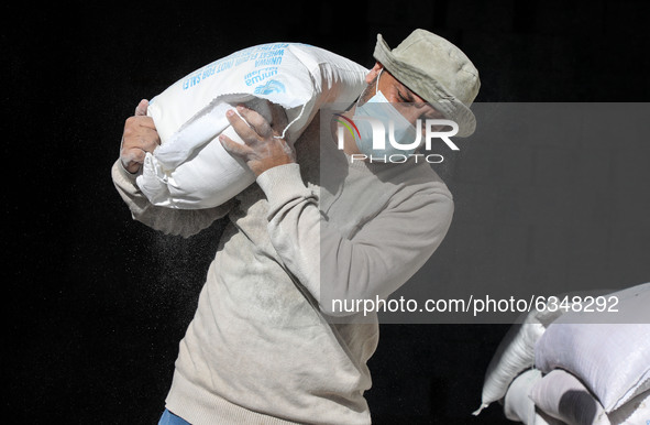 A Palestinian man carries a sack of aid food received by the United Nations Relief and Works Agency for Palestine Refugees (UNRWA), amid the...