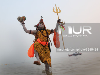 A Hindu devotee dressed as Lord Shiva stands on the beach as others take a holy dip in the Bay of Bengal during the Gangasagar Mela, at Saga...