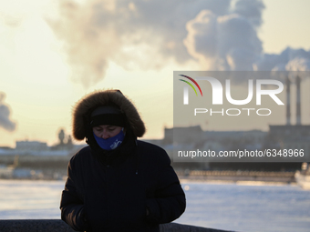 A man in a protective mask on the embankment of the Neva River during a severe frost in St. Petersburg. the temperature in St. Petersburg dr...