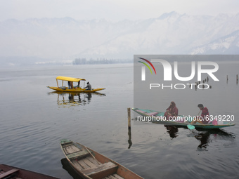 People cross the icy waters  of partially frozen Dal Lake, Srinagar, Indian Administered Kashmir on 14 January 2021.  Srinagar city witnesse...