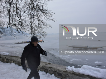 A man walks besides frozen Dal Lake, Srinagar, Indian Administered Kashmir on 14 January 2021.  Srinagar city witnessed lowest temperature o...