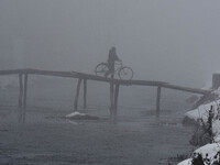 A man crossing the bridge with bicycle amid dense fog in Srinagar, Kashmir on January 15, 2021.A meteorological department official said tha...