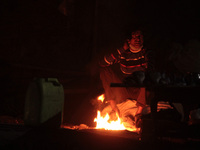 A vendor sits around a bonfire on a cold evening in New Delhi, India on January 15, 2021. The city is in the grip of its second cold wave of...