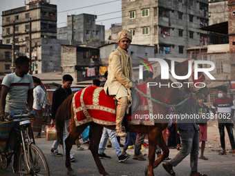 A newly married groom rides on a decorated horse as he going to get married at Keraniganj area in Dhaka, Bangladesh on Friday, January 15, 2...
