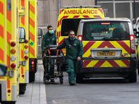 Ambulance crew walk wheel a stretcher outside the emergency department at the Royal London Hospital, on 15 January, 2021 in London, England....