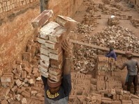 A man stacks eighteen bricks on his head while working at in brickfields Narayanganj near Dhaka Bangladesh on January 15, 2021. (