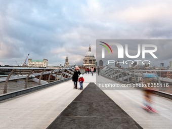 Passers-by are seen walking on Millennium Bridge on the Thames River in front of Saint Pauls Cathedrals as the UK's government introduced st...
