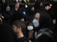 An Iranian woman wearing a protective face mask looks on while attending a religious ceremony to commemorate the death anniversary of Fatima...