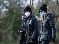  Two women wearing face masks walk in Wandsworth Common as England remains under lockdown to limit the spread of the new, more transmissible...