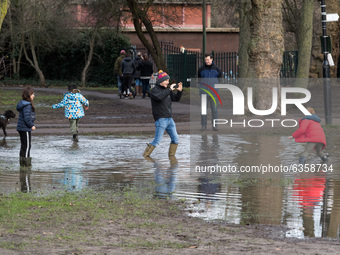  Kids and an adult stand in a large puddle in Wandsworth Common as England remains under lockdown to limit the spread of the new, more trans...