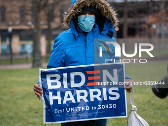 A woman holds a Biden/Harris sign during an armed protest at the Ohio Statehouse ahead of the inauguration of President-elect Joe Biden in t...