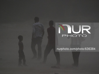 Indian people walk at holy sangam area,confluence of River Ganga,Yamuna and mythical saraswati,during heavy dust storm,in Allahabad on June...