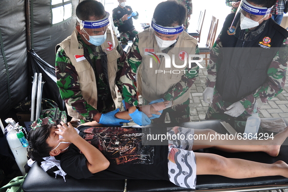 Three personnel of the Indonesian Navy's Indonesian National Armed Forces medical team are treating a broken arm of a citizen, one of the vi...