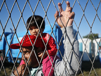 A man with a child inside refugee transfer camp in Opatovac near border crossing point between Serbia and Croatia. Opatovac, Croatia. Septem...