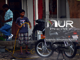 An indian minor boy washes a motor bike,on World day against child labour,in Allahabad on June 12,2015. (