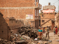 Bhaktapur locals walk past the destruction left from Nepal's two major earthquakes, last month. Most families in this area have completely l...