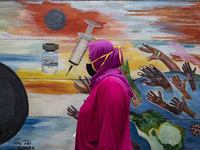 A woman passing by the mural Covid19 in Tangerang, Banten, Indonesia, on 26 January 2021. Indonesia reach out to 1 million of Covid19 positi...