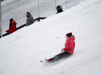 A girl speeds down a hill on a sled in Warsaw, Poland on February 13, 2021. The Polish government announced this week the reopening of cinem...