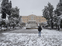 A person walks in the snow, in the center of Athens, during a rare heavy snowfall in the city on February 16, 2021. - Greece's weather agenc...