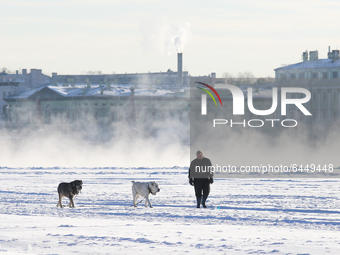 A woman with dogs walks along the frozen Neva River in St. Petersburg, Russia, on February 18, 2021.  The air temperature dropped to -27 deg...