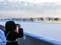 A girl photographs the morning fog on the Neva River in St. Petersburg, the air temperature dropped to -27 degrees.(