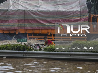 People wait for the water to subside as their vehicles are stuck on a flooded toll road following heavy rains in Jakarta, Indonesia, Saturda...
