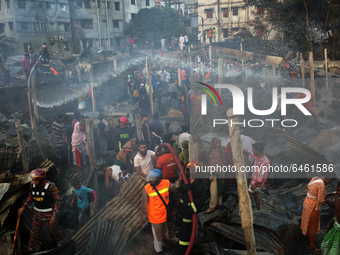 Slum Dwellers searching for their household belongings as firefighters and volunteers try to douse a fire at a slum in Dhaka, Bangladesh on...
