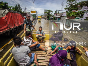 Residents ride a truck through floodwaters caused by torrential rain in Semarang, Central Java on February 24, 2021. (