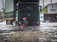 Resident push their motorbike through floodwaters caused by torrential rain in Semarang, Central Java on February 24, 2021. (