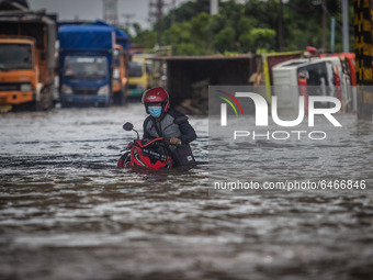Resident push their motorbike through floodwaters caused by torrential rain in Semarang, Central Java on February 24, 2021. (
