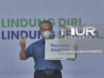 Malaysias Prime Minister Muhyiddin Yassin gestures as he hold placard I am vaccinated in Putrajaya, February 24, 2021. Muhyiddin Yassin is t...