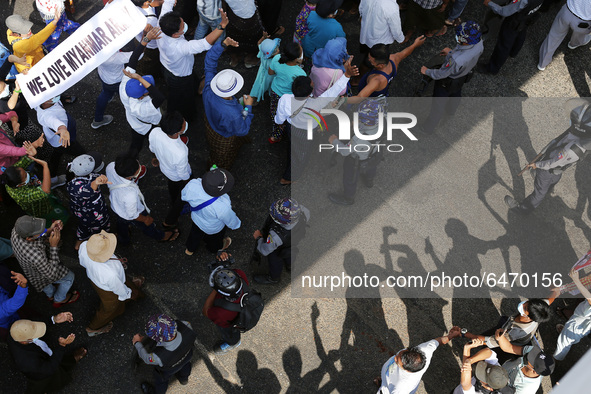Anti-military protesters cross their arms to pro-military supporters during a rally supporting the military coup in central Yangon, Myanmar...