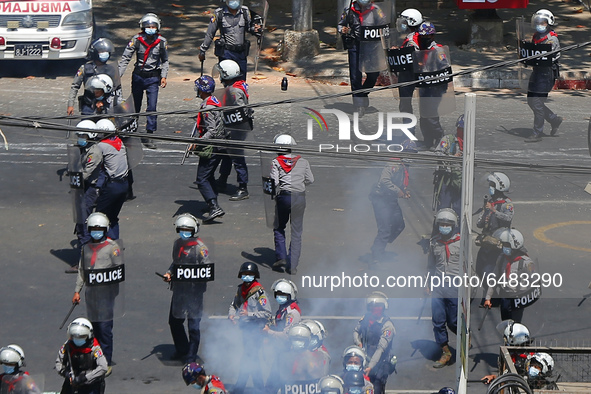 A riot policeman throws a sound hand grenade towards protesters during a demonstration against the military coup in Yangon, Myanmar on March...