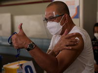 A man gives the thumbs up sign after getting inoculated with the Sinovac COVID19 vaccine during a ceremonial vaccination program held inside...