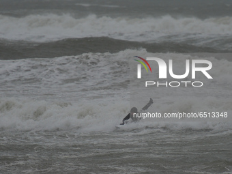 A surfer in the sea at Tramore in County Waterford on the South East coast of Ireland, where the yellow 100 km/h weather warning is in effec...