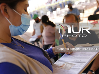 A elderly fill out a form after receive a dose of Pfizer-BioNTech Covid-19 vaccine, during mass vaccine inside of Hermanos Lopez Rayon sport...