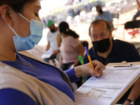 A elderly fill out a form after receive a dose of Pfizer-BioNTech Covid-19 vaccine, during mass vaccine inside of Hermanos Lopez Rayon sport...