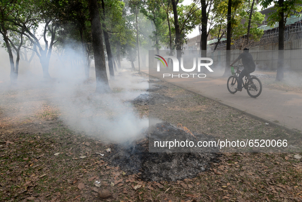 People seen moves as the garbage are burning beside a road in a park in Dhaka, Bangladesh, on March 13, 2021 
