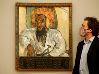 A member of staff poses beside 'Arab with Dagger', by South African artist Irma Stern, estimated at GBP700,000-1,000,000, during a press pre...